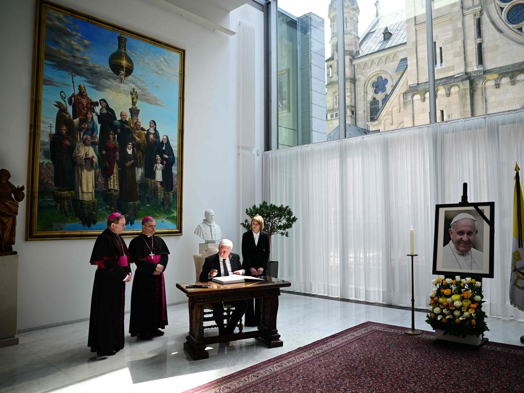 A picture of late Pope Francis is seen as German President Frank-Walter Steinmeier signs a condolence book and as his wife Elke Buedenbender, Chairman of the German Bishops' Conference Georg Baetzing and Archbishop and Apostolic Nuncio to Germany Nikola Eterovic stand at the Apostolic Nunciature in Berlin. Picture: AFP