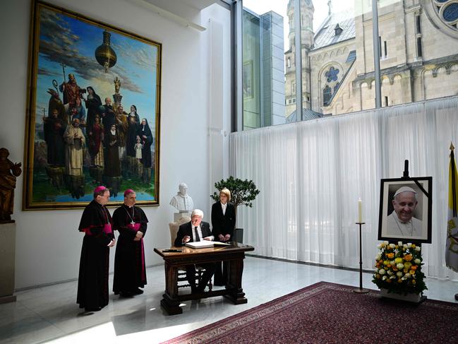 A picture of late Pope Francis is seen as German President Frank-Walter Steinmeier signs a condolence book and as his wife Elke Buedenbender, Chairman of the German Bishops' Conference Georg Baetzing and Archbishop and Apostolic Nuncio to Germany Nikola Eterovic stand at the Apostolic Nunciature in Berlin. Picture: AFP
