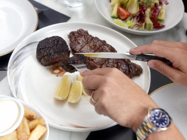 John Gambaro tucks into a steak at his restaurant Black Hide. Picture: Steve Pohlner