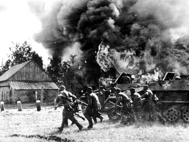 World in flames ... Nazi soldiers storm into a burning Russian village in WW2.