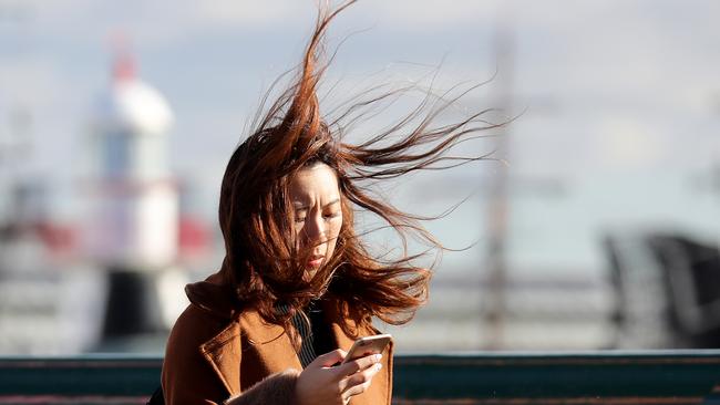 Sydneysiders brace for high winds as a cold front sweeps over the city bringing icy winds for those making their way over the Pyrmont Bridge. Picture: Toby Zerna