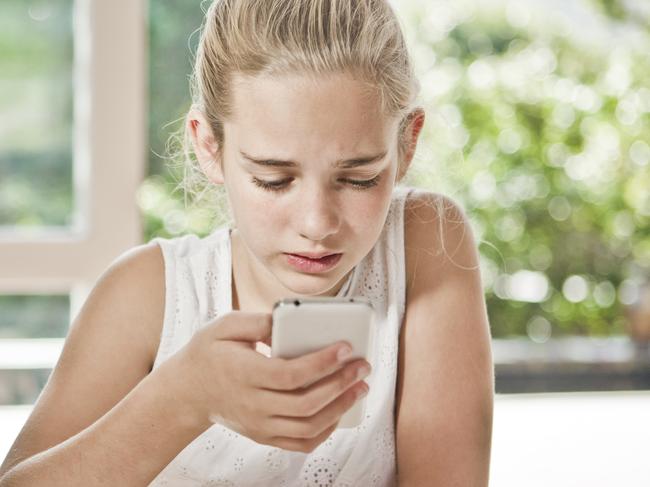 A young girl is worried, she is looking at her phone.