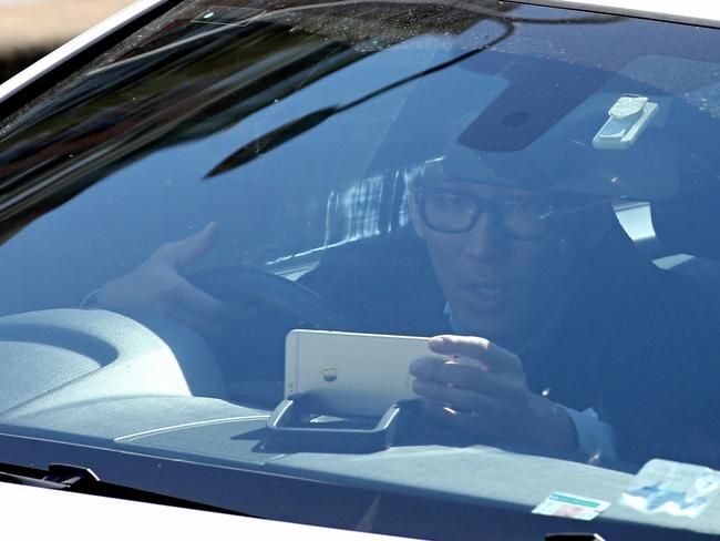 A man diverts his attention to a mobile phone on the dashboard of his vehicle on South Dowling St. Picture: John Grainger