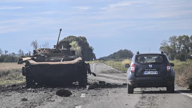 A car drives past a destroyed armored vehicle in Balakliya, Kharkiv region, on September 10. Picture: AFP