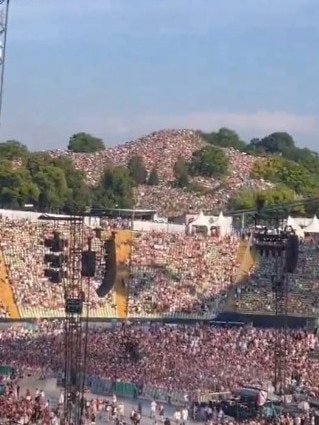 The crowd inside the stadium, and on the hill behind.