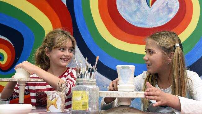 Matilda and Evie paint pottery at St Kilda Adventure Playground.