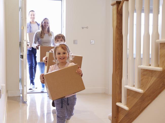 Family Carrying Boxes Into New Home On Moving Day