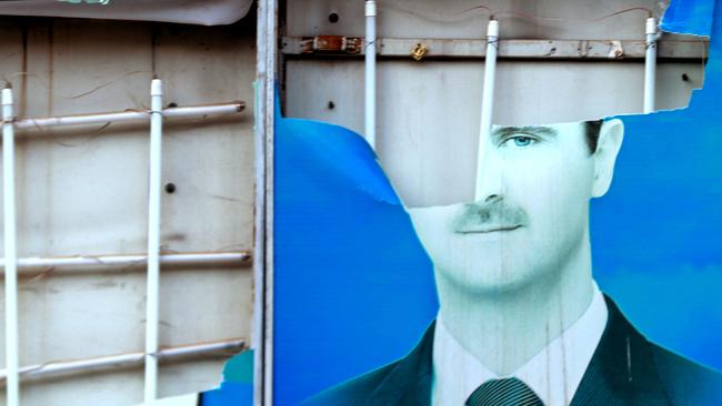 A damaged portrait of Syrian President Bashar al-Assad is hangs in the city of Qamishli, as Syrian Kurds celebrate the fall of capital Damascus to anti-government fighters.