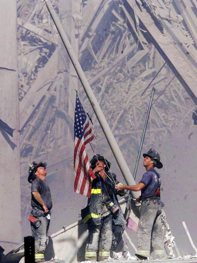 Firefighters raise a flag late in the afternoon amid the wreckage of the World Trade Centre towers in New York. Picture: AP