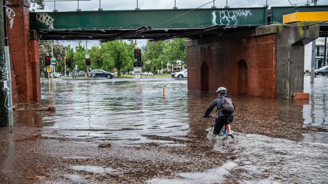 A cyclist takes a chance cycling through flood waters. Picture: Jason Edwards