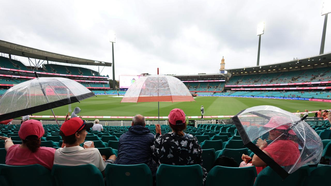 People with umbrellas look on as rain stops play on day two. Picture: Getty