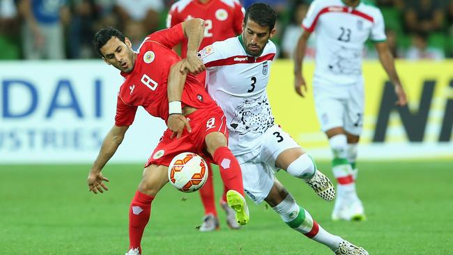 Sayed Ahmed Jaafar of Bahrain and Ehsan Hajsafi of Iran contest for the ball.