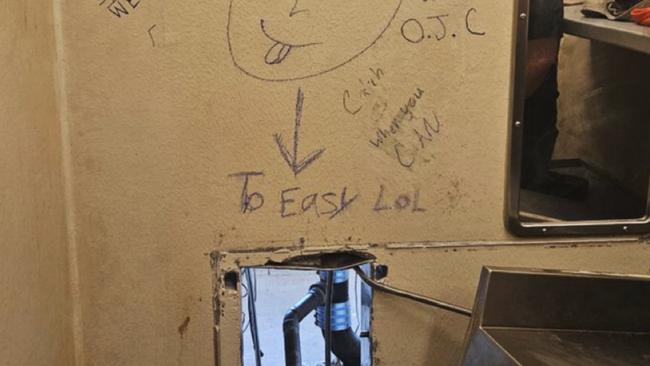 A photo released by authorities showed the opening behind the toilet in a cell where the men escaped through — complete with a taunting message scrawled on the wall that read “To Easy LoL” with an arrow pointing at the gap. Picture: AP.