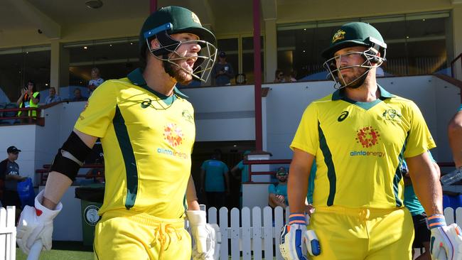 David Warner (left) and Aaron Finch walk out ot bat for Wednesday’s practice match against New Zealand in Brisbane. Picture: AAP 