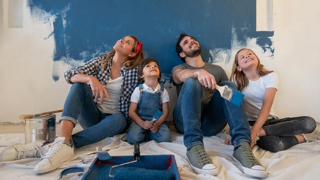 Happy family taking a break from painting their house and looking up - home improvement concepts