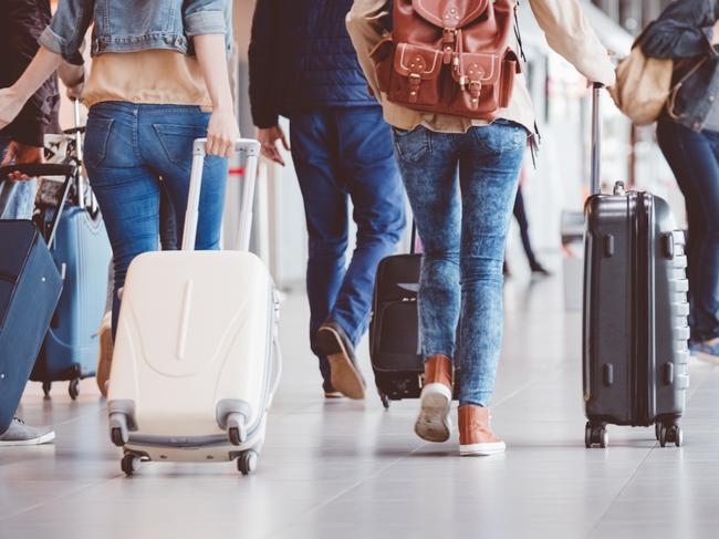 Low angle rear view of passengers walking in the airport terminal. People with luggage in airport.Escape 13 August 2023Doc HolidayPhoto - iStock