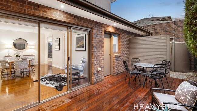 Sliding doors open to a private deck surrounded by greenery.