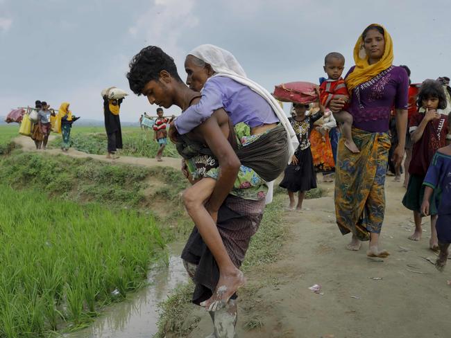 A young man helps an old woman flee Myanmar’s Rakhine state for Bangladesh. Picture: K.M. Asad