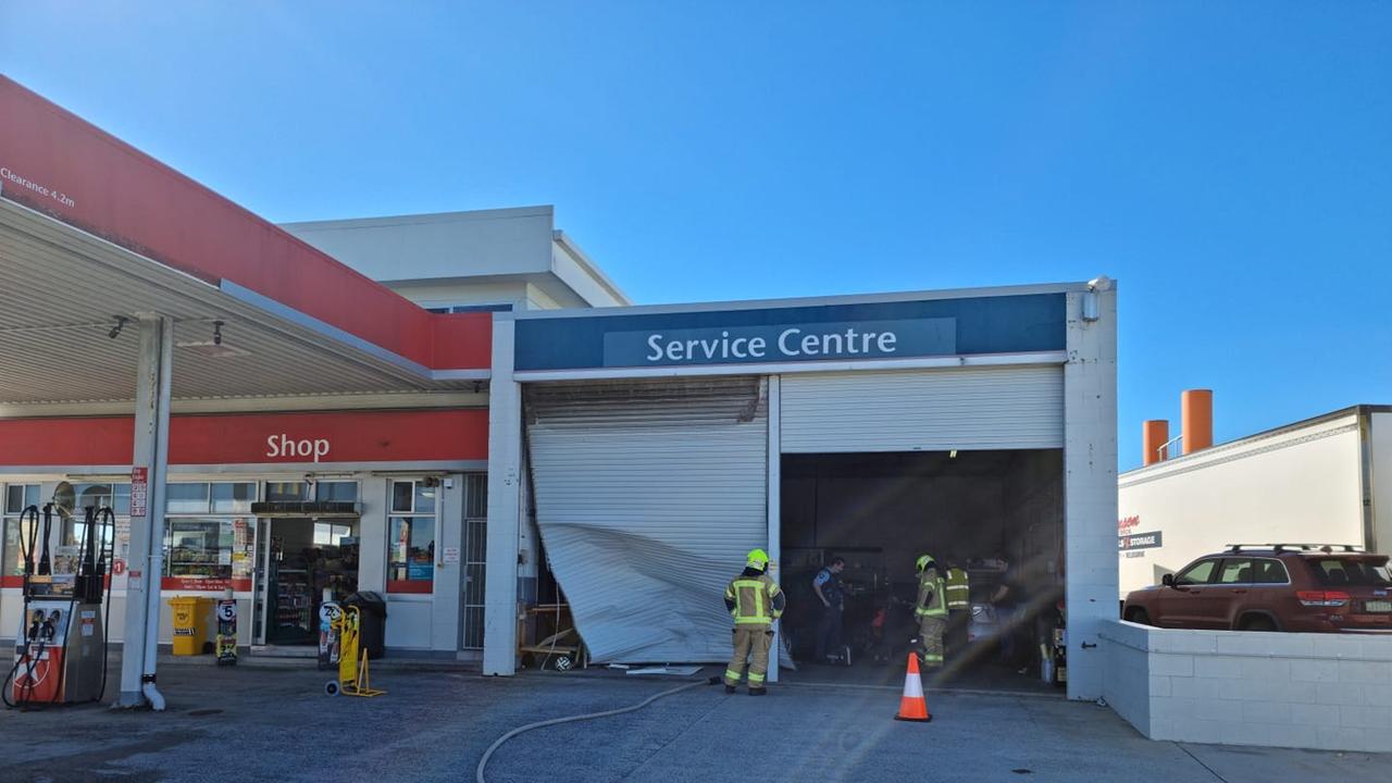 A woman was injured after she crashed through a garage door and collided with a car at a Yamba service station. Photo: Yamba Fire Rescue 510.