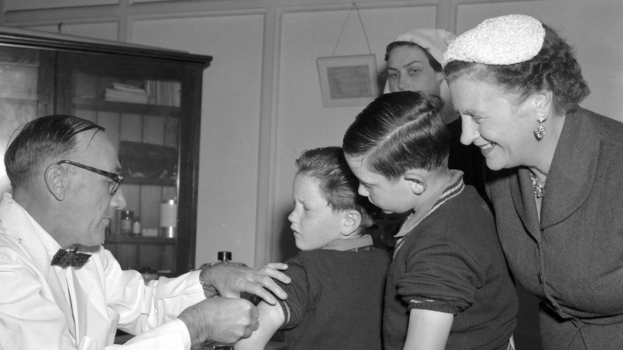 First shots of Salk anti-polio vaccine being given by Health and Medical Services deputy director Dr DW Johnson in Brisbane. On the receiving end are Clem, 7, left, and Paul, 9, sons of the Premier Vince Gair, pictured with their mother. Picture: Bob Millar Jnr