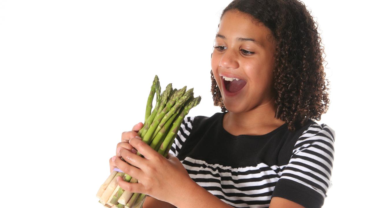 Little girl ready to eat a bunch of asparagus