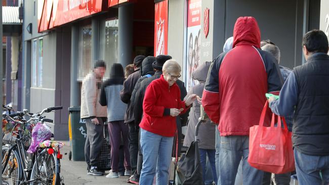 Salvation Army volunteer Sue hands out vouchers to regular user of the service, lined up at Salvation Army headquarters in Pirie Street. Picture: AAP Image/Dean Martin