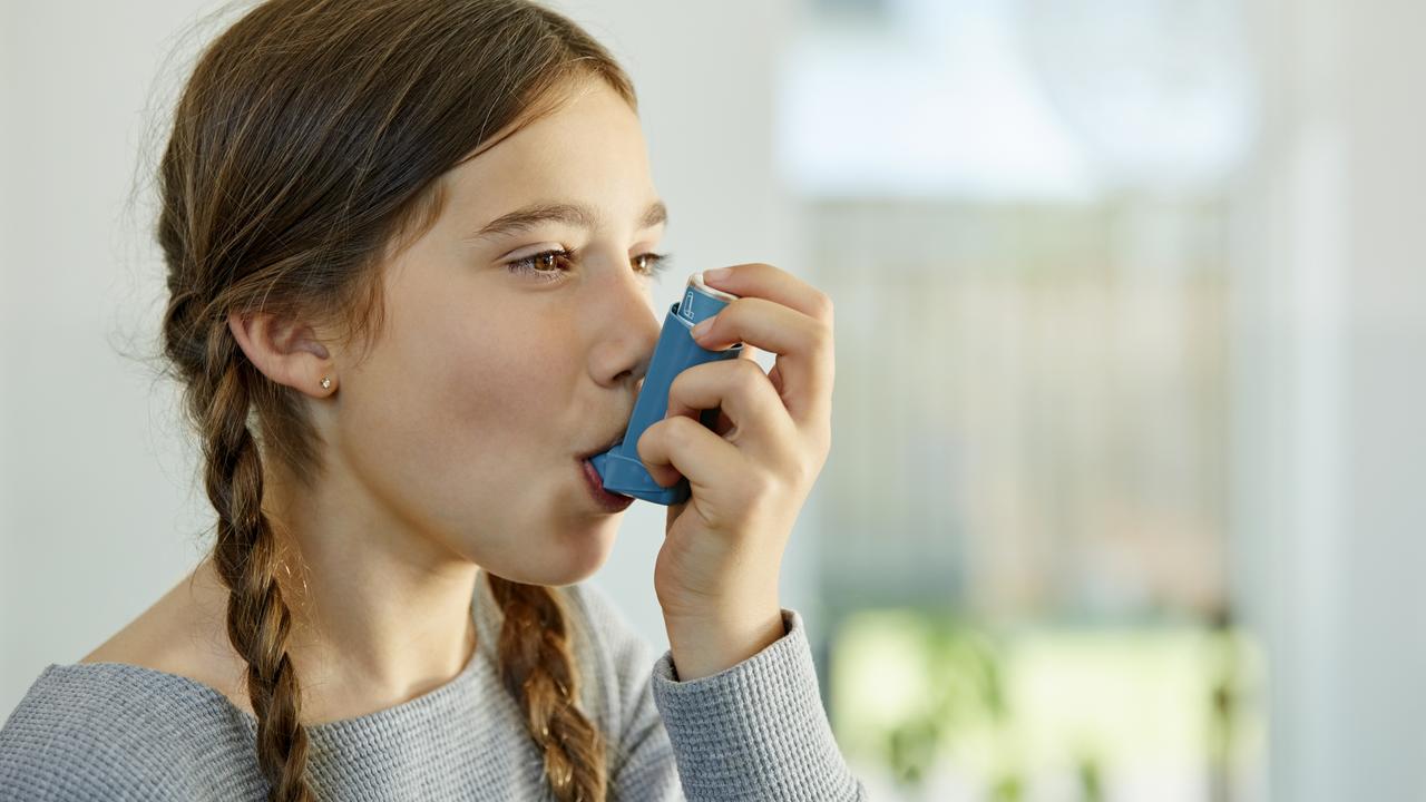 Close-up of girl using asthma inhaler at home