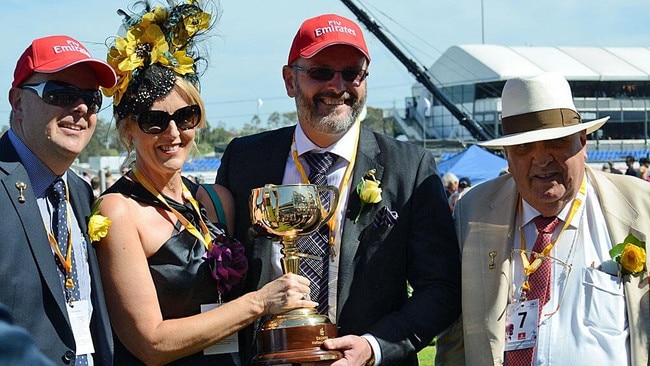 Luke and David (red hats) Henderson, David’s wife Rhonda, and their father John Henderson pictured with the Melbourne Cup after their horse Fiorente won in 2013.