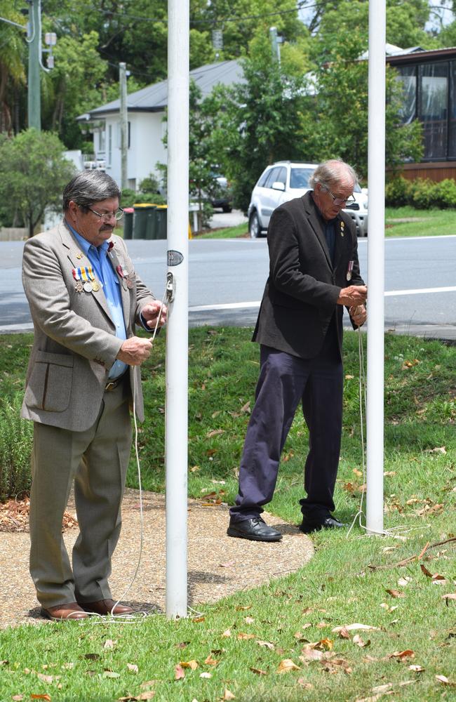 Two community members raising the flag at Yandina.