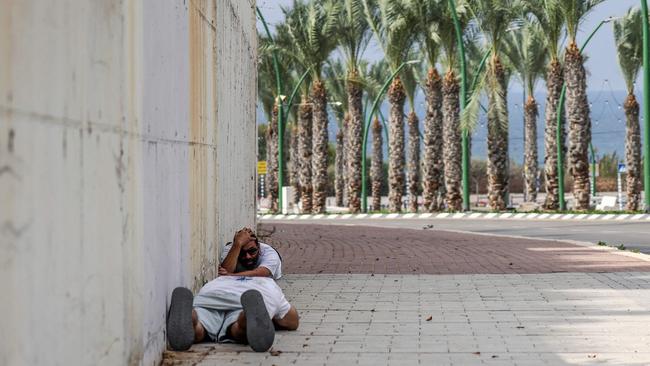 People duck for cover upon hearing sirens warning of incoming fire in the southern Israeli city of Ashkelon on October 11. Picture: AFP