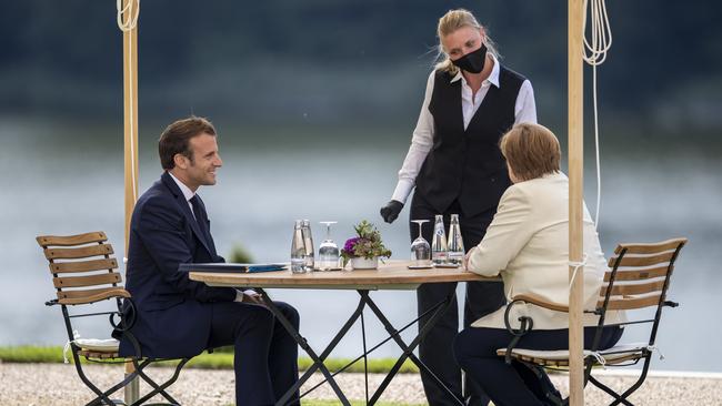 Emmanuel Macron, left, and Angela Merkel with a waitress in the garden of Schloss Meseberg. Picture: Getty Images