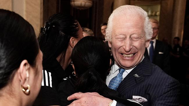 Britain's King Charles III reacts as he is hugged by members of New Zealand's Black Ferns rugby union team, at Buckingham Palace in central London on September 11, 2024. (Photo by Aaron Chown / POOL / AFP)