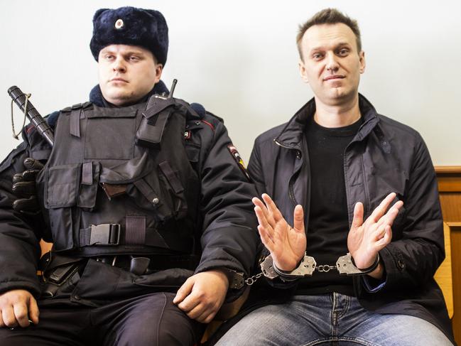 "Handcuffed" Alexei Navalny, handcuffed to a policeman, gestures to the press as he waits for an appeal hearing after his arrest at an anti-government rally in Moscow. March 30, 2017 Picture - Evgeny Feldman