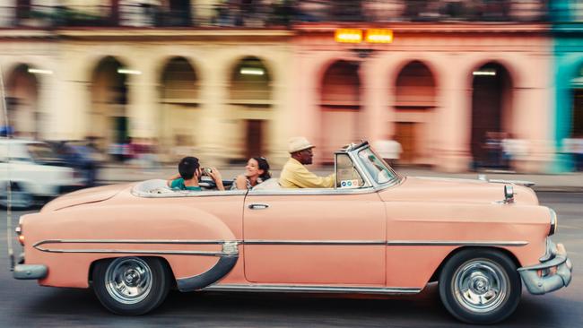 ESCAPE: Best Trends for 2018, Mal Chenu -  Havana, Cuba - March 19, 2015: Tourists ride in a classic American car that serves as a taxi, a young couple pose for a photo inside the cabriolet. Picture: Istock