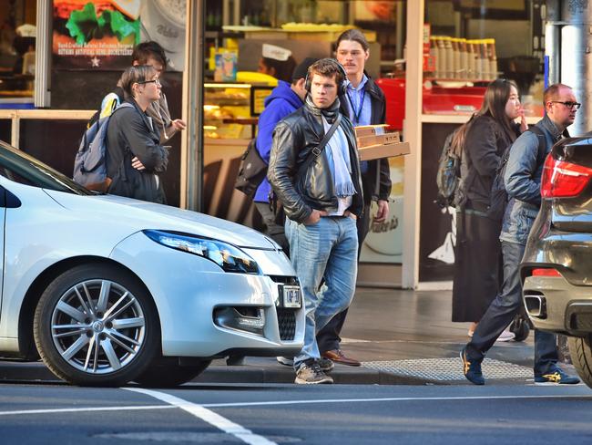 Pedestrians wearing headphones crossing Flinders street, Melbourne. Picture: Tony Gough