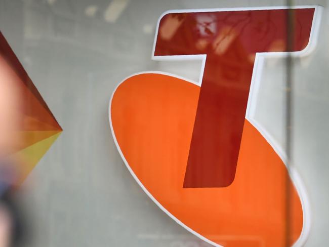 People walk past a sign of telecommunications company Telstra in Melbourne on August 16, 2018. - Australia's dominant telecommunications company Telstra on August 16 warned of "enormous challenges" ahead as it posted an 8.9 percent slump in annual profit. (Photo by William WEST / AFP)