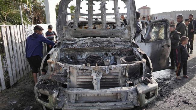 EDITORS NOTE: Graphic content / TOPSHOT - People gather around the car of the US-based aid group World Central Kitchen that was hit by an Israeli strike the previous day in Deir al-Balah in the central Gaza Strip on April 2, 2024, amid the ongoing battles between Israel and the Palestinian militant group Hamas. The international food aid charity said on April 2 it was pausing its Gaza aid operations after seven of its staff were killed in a "targeted Israeli strike" as they unloaded desperately needed food aid delivered by sea from Cyprus. (Photo by AFP)