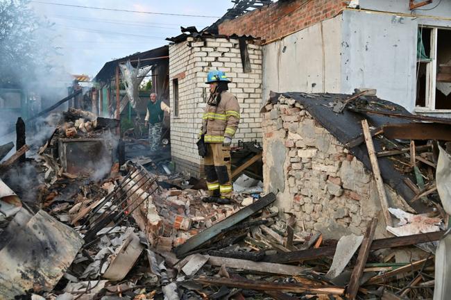 Firefighters clear debris from homes in the suburbs of Kharkiv