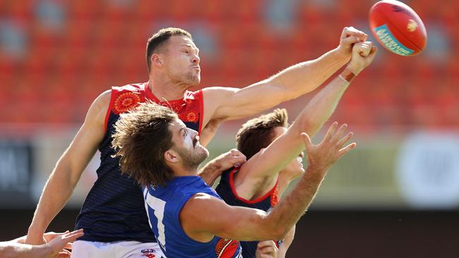 Steven May and Jake Lever of the Demons both punch the ball away from Josh Bruce of the Bulldogs. Picture: Michael Klein