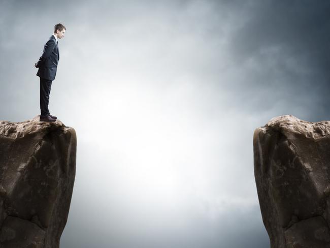 Young businessman standing on edge of rock mountain and looking