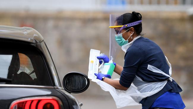 A medical worker with a testing kit for the novel coronavirus COVID-19 at a drive-in testing facility in East London.