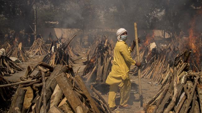 A cemetery worker walks among burning funeral pyres of patients who died of Covid-19 at a crematorium in New Delhi, India. Picture: Getty Images