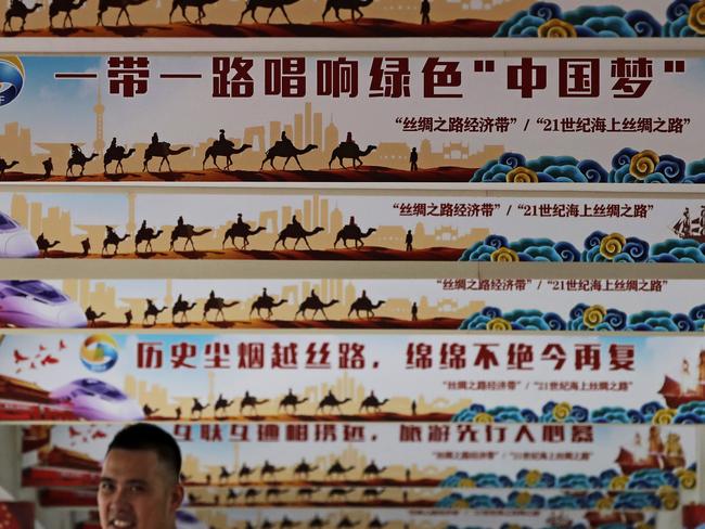 In this Friday, June 29, 2018, photo, a man stands underneath the pillars displaying Chinese President Xi Jinping's signature "China Dream" and "One Belt, One Road" foreign policy plan during an event in Beijing. China's June trade grew by double digits amid mounting tension with Washington but the government warned it will face "rising instabilities and uncertainties." (AP Photo/Andy Wong)