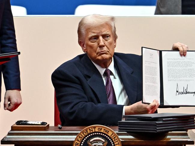 US President Donald Trump signs executive orders during the inaugural parade inside Capital One Arena, in Washington, DC, on January 20, 2025. (Photo by ANGELA WEISS / AFP)