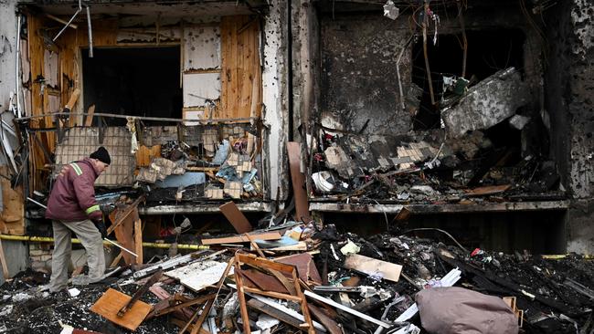 A man clears debris at a damaged residential building at Koshytsa Street, a suburb of the Ukrainian capital Kyiv. (Photo by Daniel LEAL / AFP)