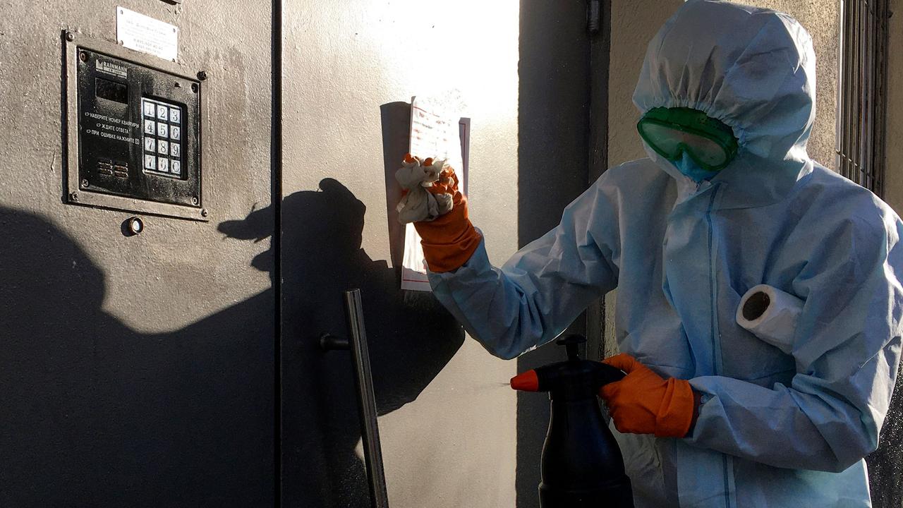 A communal worker sprays disinfectant on the door of a residential building in Moscow on April 11, 2020, amid the COVID-19 coronavirus pandemic. Picture: AFP