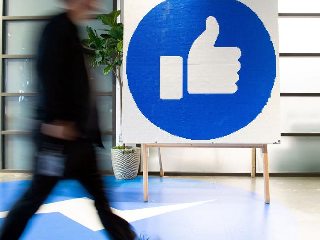 (FILES) This file photo taken on October 23, 2019 shows a Facebook employee walking past a sign displaying the "like" sign at Facebook's corporate headquarters campus in Menlo Park, California. - Facebook was branded "arrogant" and "unconscionable" for banning Australian users from sharing news on February 18, 2021, as its defiant response to government regulation inadvertently crippled the pages of several emergency services. (Photo by Josh Edelson / AFP)