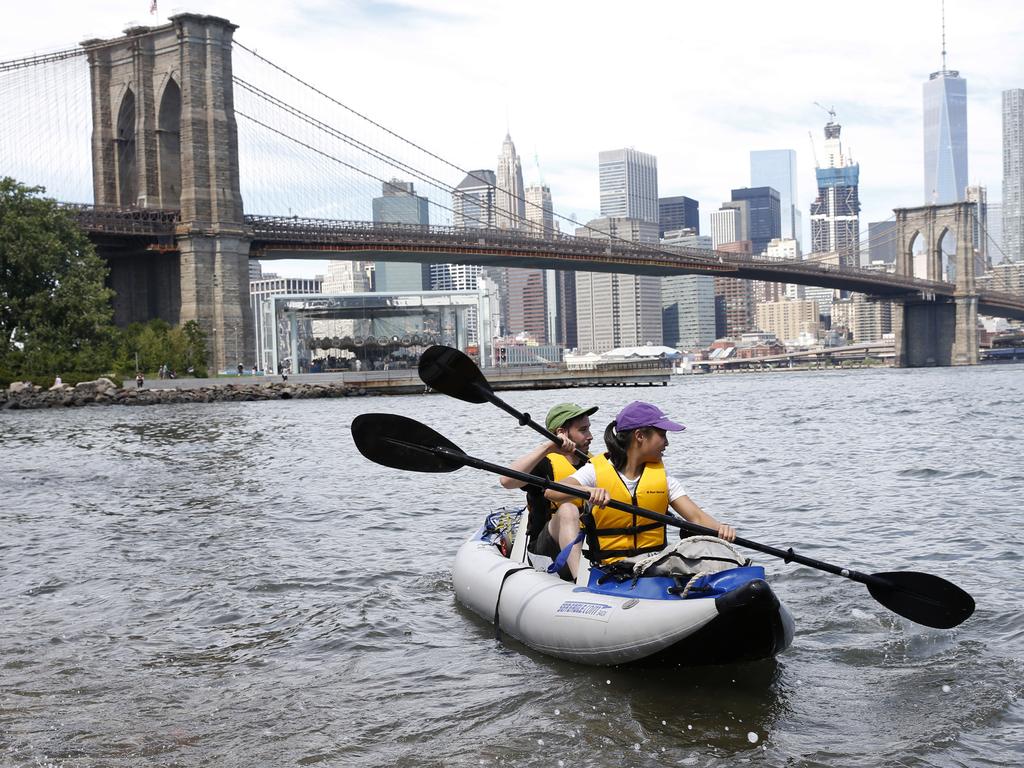 A couple paddles in their inflatable kayak in the East River with the Manhattan skyline behind them after stopping on a small beach in Brooklyn Bridge Park, Sunday, July 24, 2016, in New York. People tried to find ways to beat the heat as a spell of hot weather continued into its fourth day. Picture: AP Photo/Kathy Willens