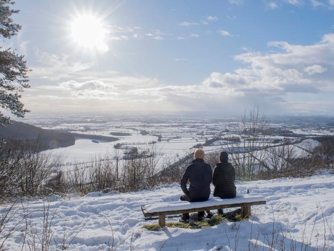 A couple sit on a bench overlooking the snow-covered fields of Thirsk at Sutton bank National Park Centre in the North Yorks Moors National Park in North Yorkshire, on February 27, 2018. A blast of Siberian weather sent temperatures plunging across much of Europe on Tuesday, causing headaches for travellers and leading to several deaths from exposure as snow carpeted palm-lined Mediterranean beaches. Picture: AFP
