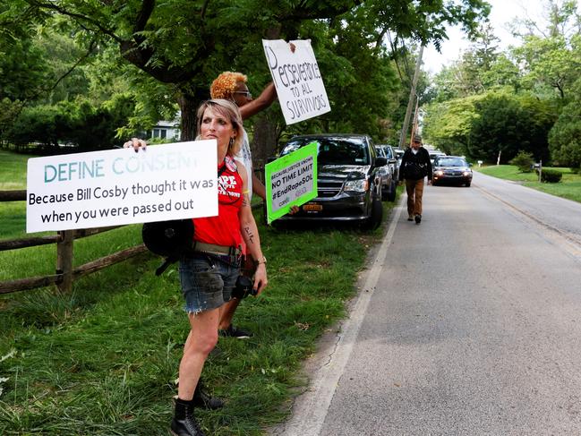 Protesters hold placards on the road outside Bill Cosby's house. Picture: Reuters.